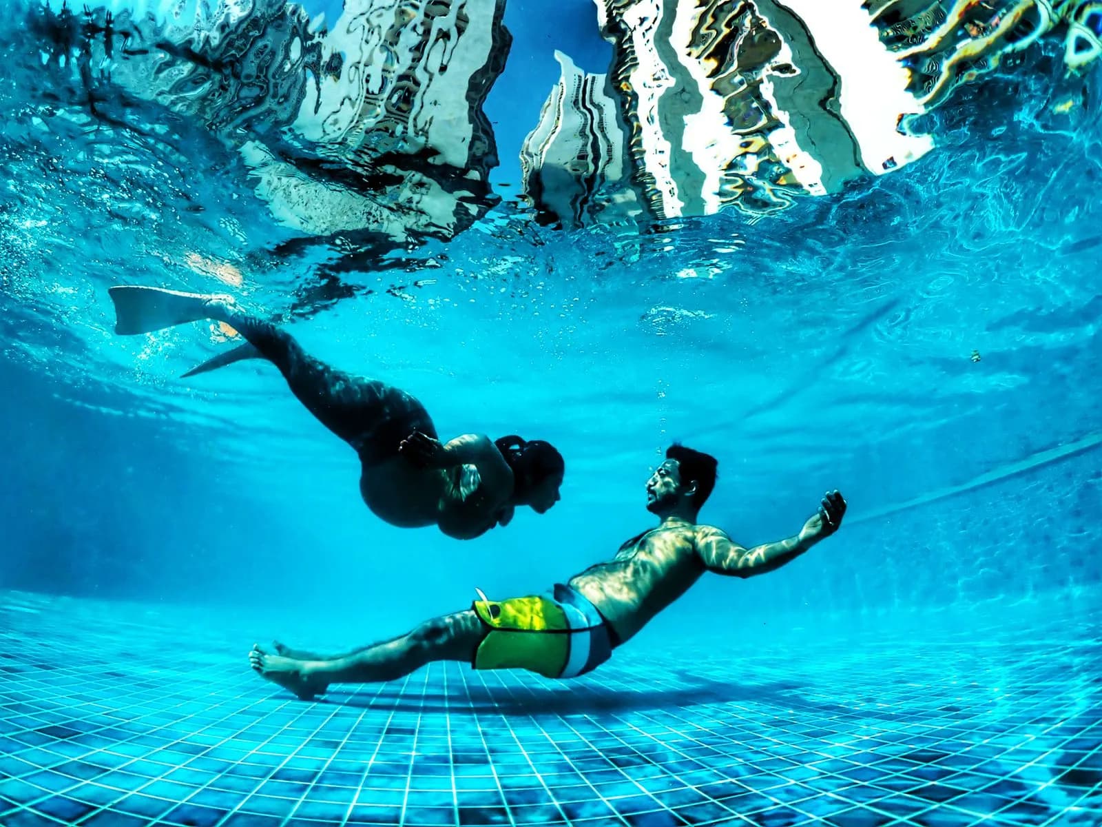 Underwater portrait of a couple floating in clear turquoise water with sun rays — SSI Specialty Photography Course